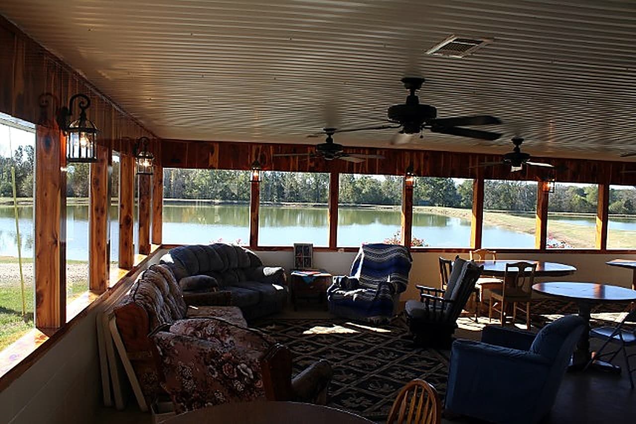 The covered lakeside lounge at Sunrise Catfish Farm with couches and big windows overlooking the ponds